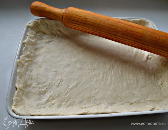 Тесто разморозить. Раскатать на слегка  присыпанной мукой поверхности по размеру формы, оставляя немного теста на "бортики". Форму для выпечки смазать растительным маслом. Уложить тесто.