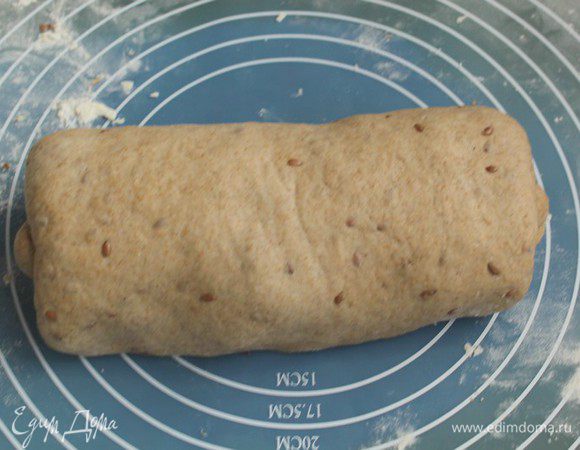 Готовое тесто выложите на рабочий стол, припылив его мукой.

Руками расплющите тесто в лепешку, в затем заверните края, как будто складывая конверт.
Затем получившийся конверт сверните рулетом.