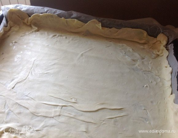 Духовку разогрейте до 180 градусов. Раскатайте тесто и выложите его на противень, застеленный бумагой для выпечки. Сделайте небольшие бортики.