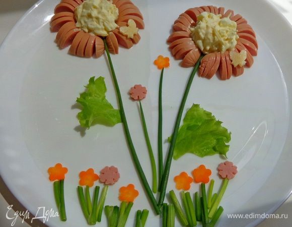 Сосиски разрезать вдоль на 2 части, на каждой сделать надрезы и свернуть в кольцо. В него положить салатик (у меня яйцо с сыром и сметаной).