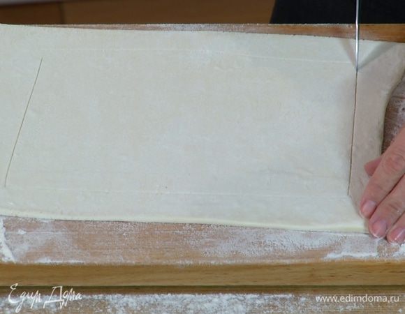 Отступая на 1 см от краев теста, не прорезая его насквозь, ножом прочертить прямоугольник меньшей площади, чтобы получились бортики. 