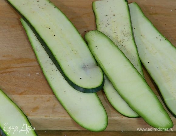 Цукини нарезать вдоль тонкими полосками, посолить и поперчить.