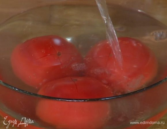 Помидоры надрезать крестом, поместить в глубокую посуду и залить кипятком, дать постоять пару минут, затем обдать ледяной водой и снять кожицу.