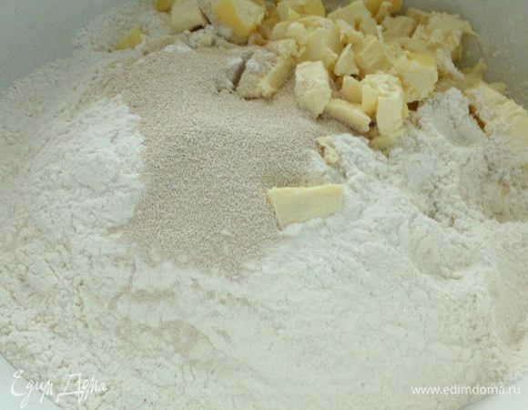 Муку просеять, добавить пакетик сухих дрожжей, щепоть соли и нарезанный кубиками охлажденный маргарин. Перетереть до состояния крошки.