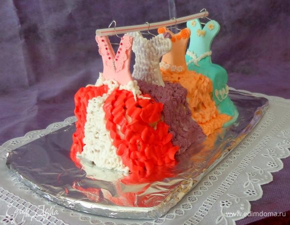 Воткнуть палочки с верхними частями платьев в торт и с помощью разноцветного крема (тот, который белковый) нарисовать низ платьев. Из подручных материалов (у меня трубочка для коктейля) сделать основу для вешалки.