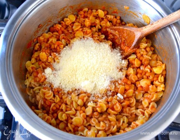 Готовую пасту слейте, сохранив предварительно немного воды. Добавьте её в кастрюлю к чечевице. Перемешайте и добавьте по желанию немного жидкости от варки макарон. Снимите всё с огня и добавьте тертый сыр пармезан. Перемешайте и подавайте!