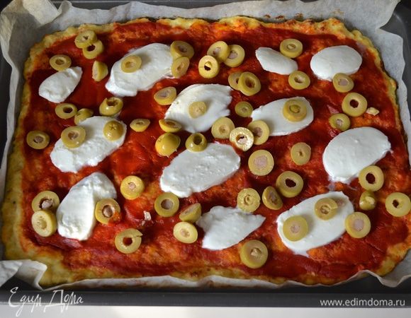 Через 15 минут достать противень и выложить на "пиццу" нарезанные предварительно сыр моцарелла и зеленые оливки. 