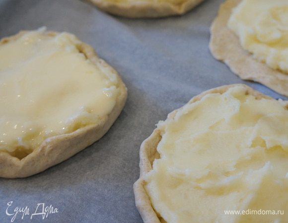 Духовку разогреть до 200 градусов. Лист застилаем пергаментной бумагой. Берём тесто и делим примерно на 8 частей. Я формирую шанежки сразу на листе - просто руками раскатываю тоненько тесто (примерно 0,5 см), выкладываю пюре, руками формирую вокруг него небольшие бортики.

Когда все шанежки сформированы сверху ложкой выкладываю заливку. 
Выпекаю минут 15-20 до зарумянивания.

Из этого количества у меня получилось 8 шанежек диаметром около 12 см.