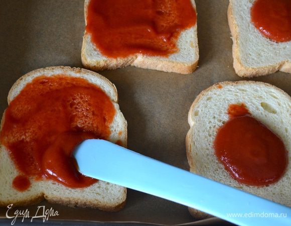Духовку включить на 200 градусов.
На противень застеленный пекарской бумагой выложите ломтики хлеба. Смажьте его томатным соусом (пассата).