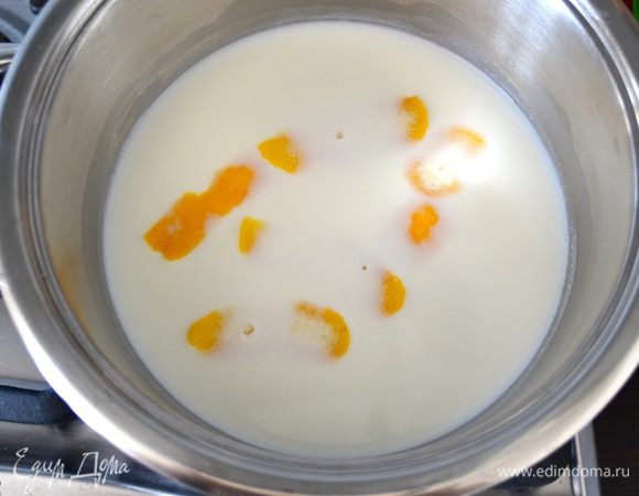 Тем временем приготовьте крем. В кастрюлю налейте молоко и добавьте срезанную цедру половины лимона. Поставьте закипать на огонь. 