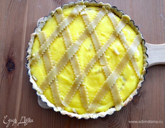 Оставшееся тесто раскатайте в тонкий пласт, нарежьте полосочки фигурным ножом (или обыкновенным ножом) и выложите поверх крема решёткой... Выложите по поверхности оставшиеся орешки.