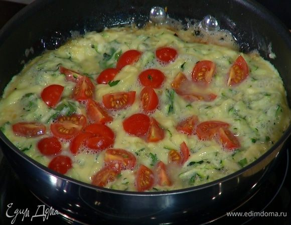 Посыпать омлет оставшимся российским сыром, выложить порезанные помидоры, накрыть сковороду крышкой и готовить еще 2–3 минуты.