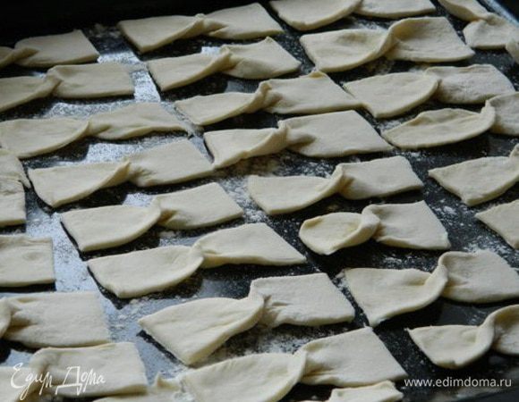 Каждый прямоугольник свернуть в виде бантика (как будто заворачиваем конфету) и уложить на противень, предварительно посыпав его мукой.