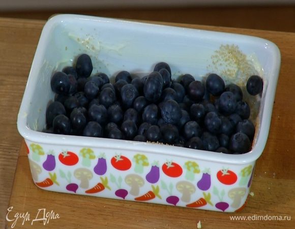 Небольшую жаропрочную керамическую форму смазать оставшимся сливочным маслом, посыпать оставшимся сахаром и выложить голубику.