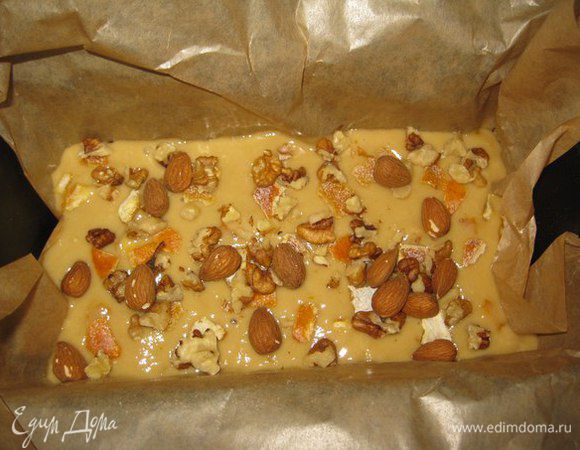 Форму высылаем пекарской бумагой. Выливаем туда тесто. Нарезаем цукаты. Добавляем орехи.