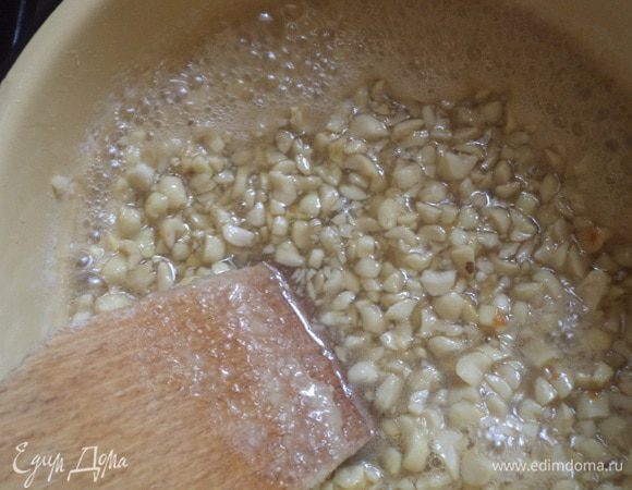 Теперь готовим грильяж. Арахис поджарить на сухой сковороде. Остудить и очень мелко порубить ножом.
В кастрюле с толстым дном в воде растворить сахар и варить, часто помешивая деревянной лопаткой, на небольшом огне до золотистого цвета.
Добавить арахис и проварить 1 минуту.
