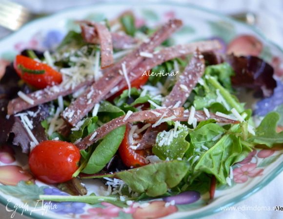 Выложить в тарелки смесь с овощами, сверху выложить салями полосками, полить заправкой и посыпать сыром пармезан тертым.
