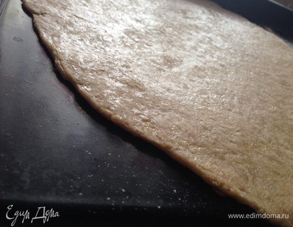Тесто тонко раскатать на рабочей поверхности, присыпанной мукой. Потом аккуратно перенести на противень, застеленный бумагой для выпечки.