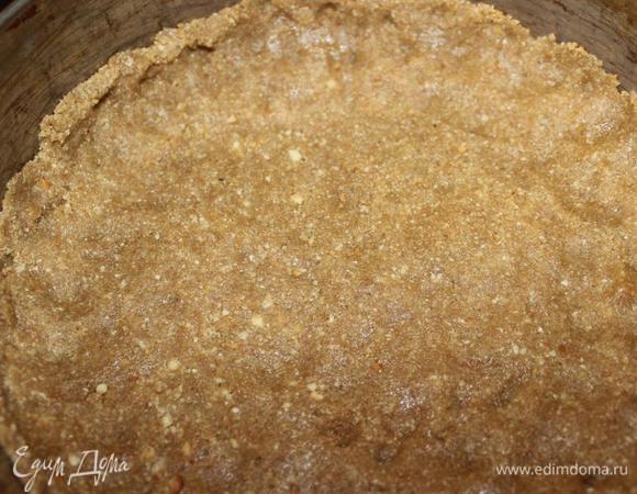 Выкладываем получившееся "тесто" в разъемную форму 21 см, дно которой застелено пергаментом, и утрамбовываем, делая невысокие бортики. 
