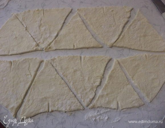 Размороженное тесто раскатать в прямоугольный пласт, разрезать на треугольники среднего размера.