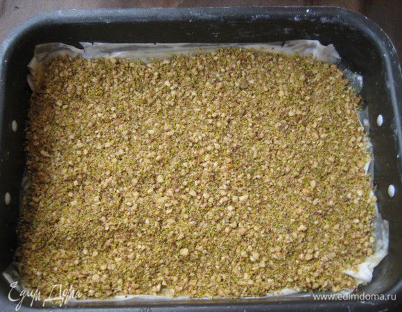 Форму смазать сливочным маслом, выложить первый лист фило, смазать маслом, выложить 3 слоя фило, каждый смазывать маслом. Выложить половину орехов, разровнять.