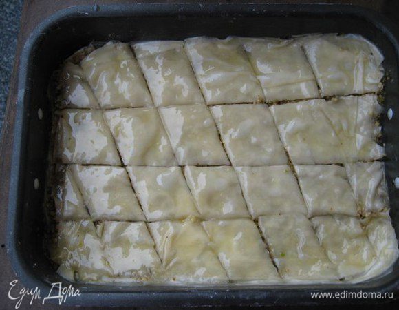 Выложить снова 3-4 слоя фило, каждый слой смазывать сливочным маслом кисточкой, выложить вторую половину орехов. Поверх орехов выложить 3 слоя фило, не забывая смазывать маслом, разрезать пахлаву на ромбики или квадраты не касаясь дна формы. 