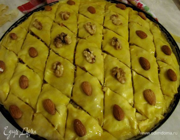 Теперь раскатайте последний 12 кусочек теста и накройте им 11 пласт.
Верх смажьте взбитым яйцом, чтобы наша пахлава была румяная и красивая.
Разрежьте пахлаву на традиционные ромбики. Режем не до конца, иначе все вытечет на дно формы и будет гореть. Поэтому режем почти до конца.
Затем на серединку каждого ромбика кладем половинку грецкого ореха, слегка прижимая (можно положить миндаль). Готово! 