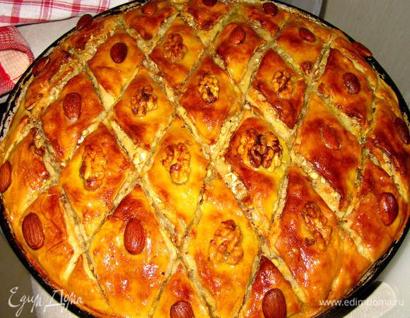 Готовим сироп. Сироп готовится просто: смешайте мед с горячей водой. 
Медовым сиропом нужно поливать почти перед самой готовностью. Т.е., когда пахлава станет золотистая, но еще будет чуть-чуть бледновата, снова достаем ее из духовки и поливаем по разрезам медовым сиропом (перед поливанием сиропом можно еще раз пройтись по разрезам ножичком). 
Сиропа уйдет где-то треть. Теперь пахлаву можно допечь до красивого красноватого цвета. Достаньте ее из духовки, накройте полотенцем и дайте немного остыть, градусов до 40-45.