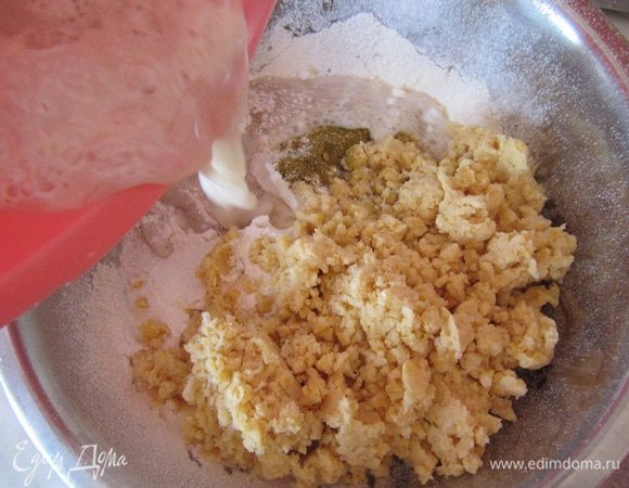 В миску положите цельнозерновую муку, а пшеничную муку просейте. Добавьте, соль, хмели-сунели, измельченный нут и влейте опару.