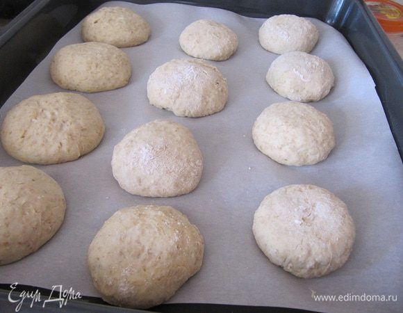 Рабочую поверхность посыпать мукой, выложить тесто, разделить на 12 равных частей, сформируйте булочки.
Противень выстелить пекарской бумагой, выложить булочки, оставить на полчаса.
