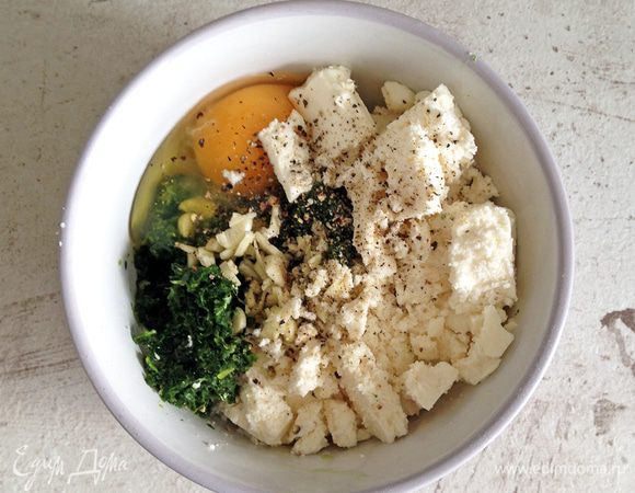 Шпинат размораживаем и очень хорошо отжимаем. Чеснок мелко нарезаем, фету крошим. Смешиваем в миске шпинат, фету, яйцо, чеснок, соль и перец.