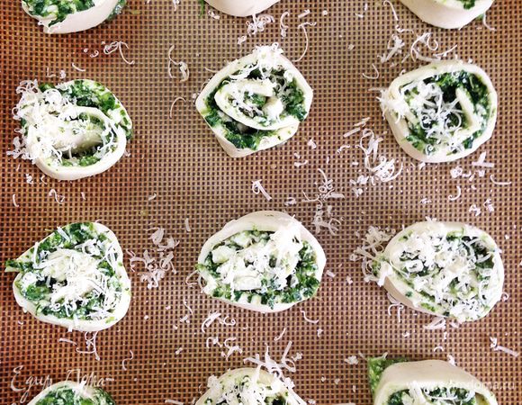 Выкладываем завитки на коврик для выпекания. Посыпаем мелко натертым пармезаном. Отправляем в разогретую до 200 С духовку на 20-25 минут до золотистой корочки.