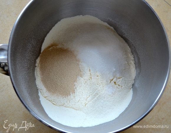 В большую миску просейте муку, добавьте сахар, ванилин, сухие дрожжи, щепотку соли и  перемешайте.