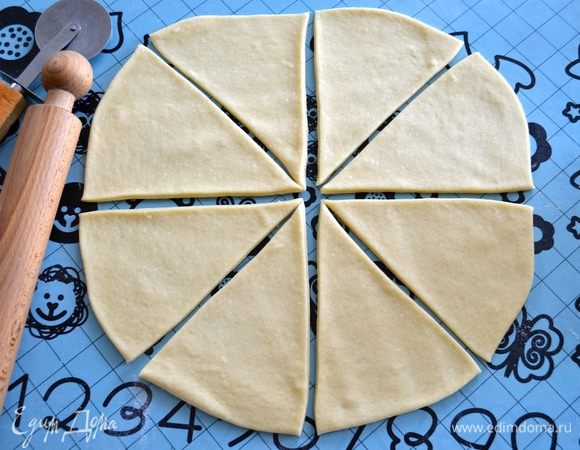 Выложите его на рабочую поверхность и разделите на 2 части (весом от 450 до 500 г). Одну часть теста раскайте в круг и разделите на 8 сегментов.