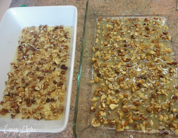 Орехи нарубить крупно, можно даже оставить четвертинки ядер. Смешайте воду, масло, сахар и мед. На медленном огне помешивайте только до растворения сахара. В глубокие формы для выпечки (можно и один большой глубокий противень) вылить сахарно-масляный сироп, выложить орехи.