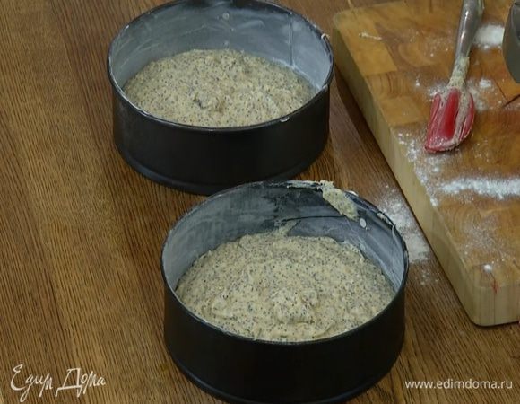 Две одинаковые разъемные формы для выпечки смазать сливочным маслом, присыпать мукой дно и бортики и равномерно выложить тесто.