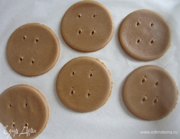 Затем на пергаменте раскатываем тесто, вырезаем кружочки, протыкаем дырочки.