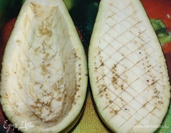 Баклажан разрезаем пополам. Осторожно делаем глубокие надрезы в виде сеточки, но не прорезаем кожуру. Мякоть баклажана вынимаем, она пойдет в начинку, а половинки присыпаем солью. Даем им постоять 4-5 минуты, промываем под проточной водой и высушиваем салфеткой.