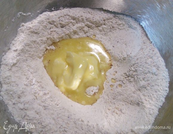 Сделайте в смеси лунку и влейте размягченное масло, замесите руками тесто. 