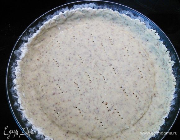 Форму смажьте маслом и посыпьте мукой. Тесто распределите по форме, формируя бортики. Тесто наколите в нескольких местах вилкой, накройте плёнкой и поставьте в холодильник на 1 час. 