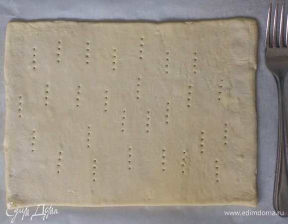 Разморозить слоеное тесто при комнатной температуре. Раскатать, придав форму прямоугольника, сделать наколы вилкой