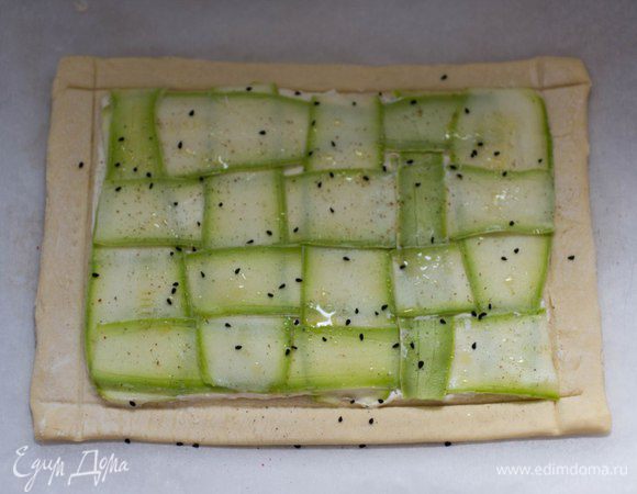 Цукини (или кабачок) нарезать тонкими пластиками. Выложить на начинку в виде плетенки. Сбрызнуть оливковым маслом, посыпать черным тмином