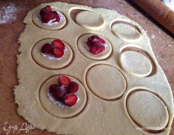 Центр половинки заготовок присыпать крахмалом, положить начинку (у меня клубника, примерно ушло грамм 100) и по необходимости начинку посыпать сахаром.