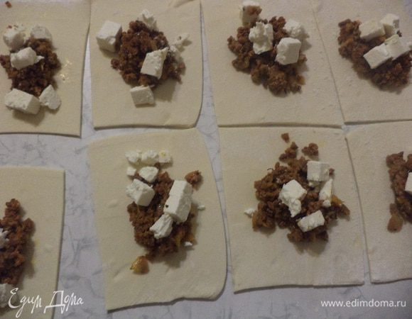 В центр каждого квадрата положить по столовой ложке начинки, сверху на начинку выложить кубики феты.