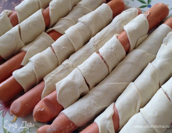 Каждую сосиску обвить полоской теста.