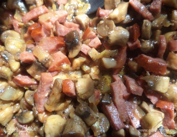 В сковороде разогреть растительное масло, выложить лук, обжарить до золотистого цвета. Добавить грибы, обжарить. Теперь добавить колбасу и томатную пасту, посолить, перемешать, обжарить. Выключить огонь.