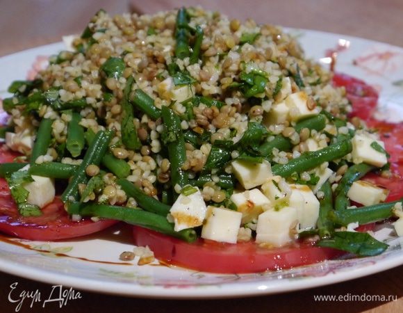 Помидор нарезать тонкими кружками поперек, выложить на тарелку в один слой, сбрызнуть оставшимся оливковым маслом, посолить и поперчить, в центр выложить салат.