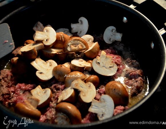 Добавить очищенные и порезанные грибы, мелко порубленный чеснок. Обжаривать, помешивая, 8 мин.