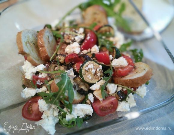 В салатницу  выложить руколу, овощи, четвертинки помидоров. Полить заправкой. Раскрошить фету и сдобрить гренками. Остальные гренки подать дополнительно. 