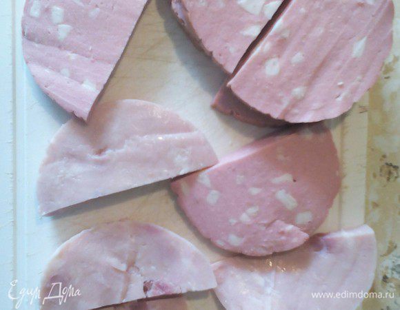 Ветчину и колбасу режем на полукруглые ломтики.